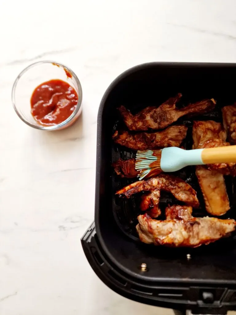 brushing bbq sauce on pork ribs