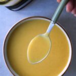 butternut and split red lentil soup in a bowl with a spoon held above it