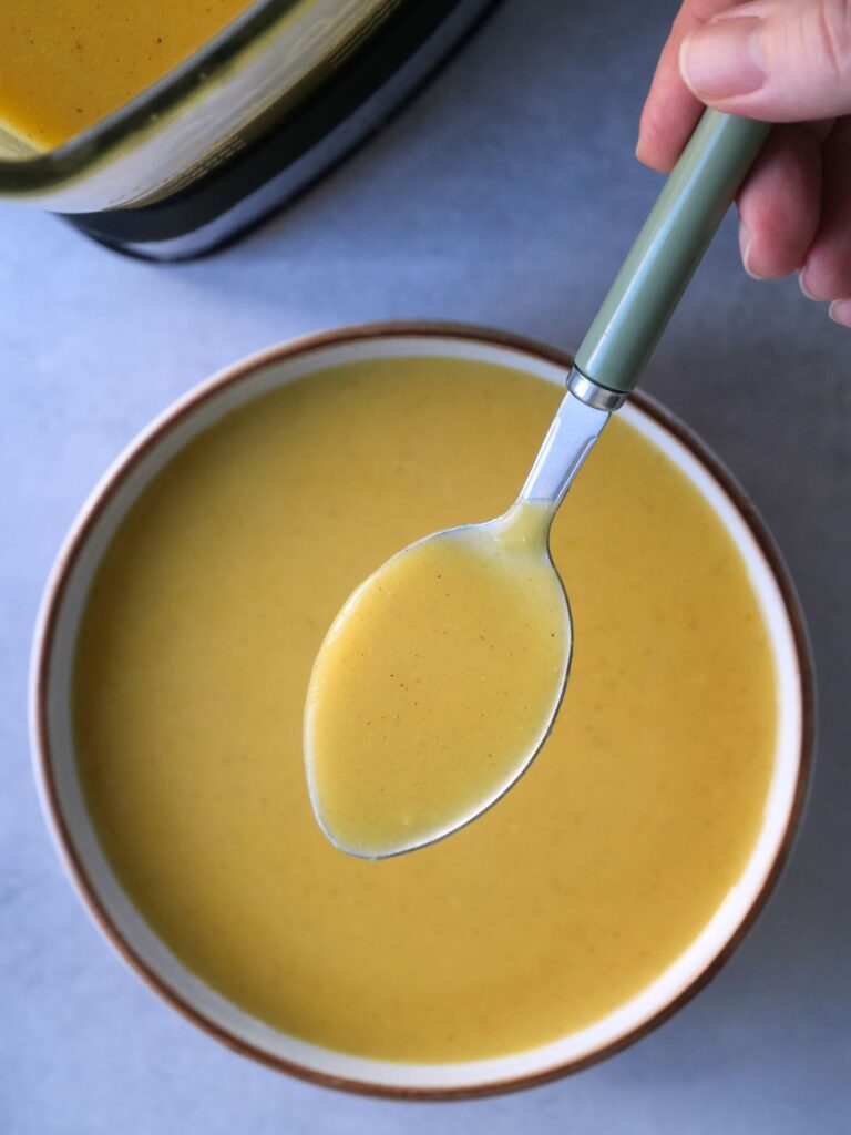 butternut and split red lentil soup in a bowl with a spoon held above it