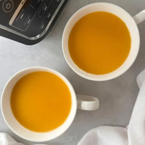 coconut chilli butternut squash soup served in two soup cups with part of the base of the ninja soup maker in the corner