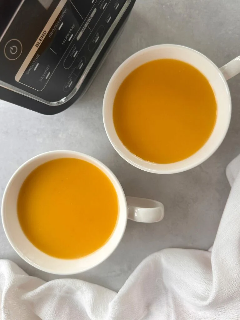 coconut chilli butternut squash soup served in two soup cups with part of the base of the ninja soup maker in the corner