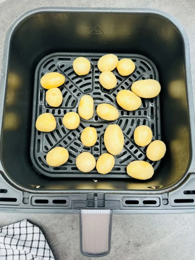 canned new potatoes in air fryer basket ready to be cooked