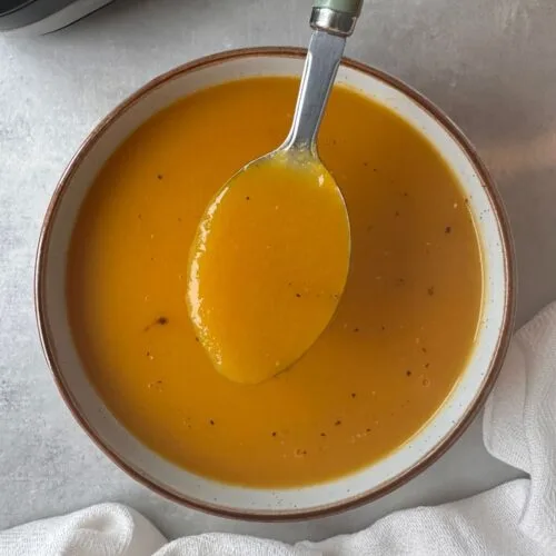 carrot and celery soup in a bowl next to a ninja soup maker