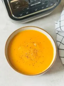 carrot and sweet potato soup in a bowl next to a Ninja Soup Maker