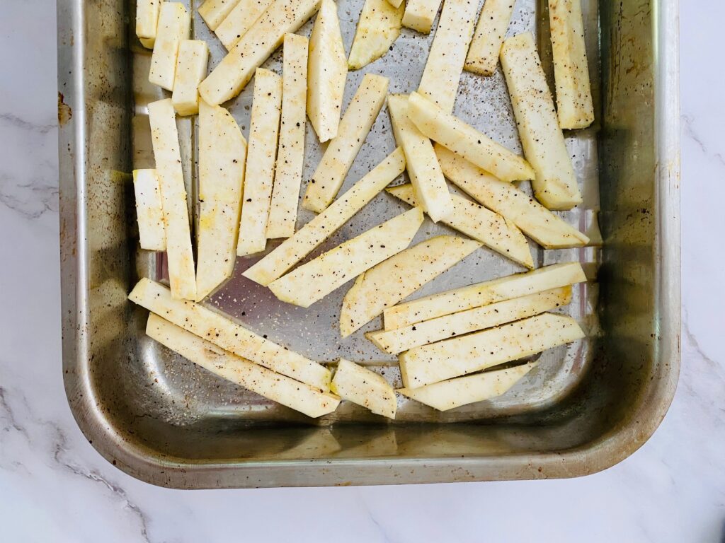 seasoned celeriac chips in a baking tin