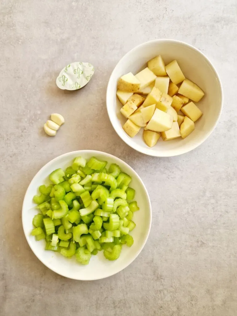 ingredients for celery soup in a soup maker - chopped potato, garlic cloves, celery and vegetable stock