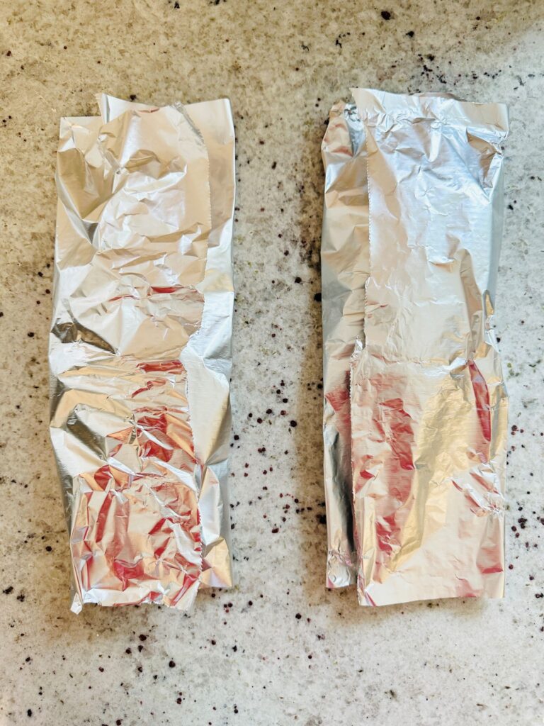 two foil packets with a chicken breast in each one