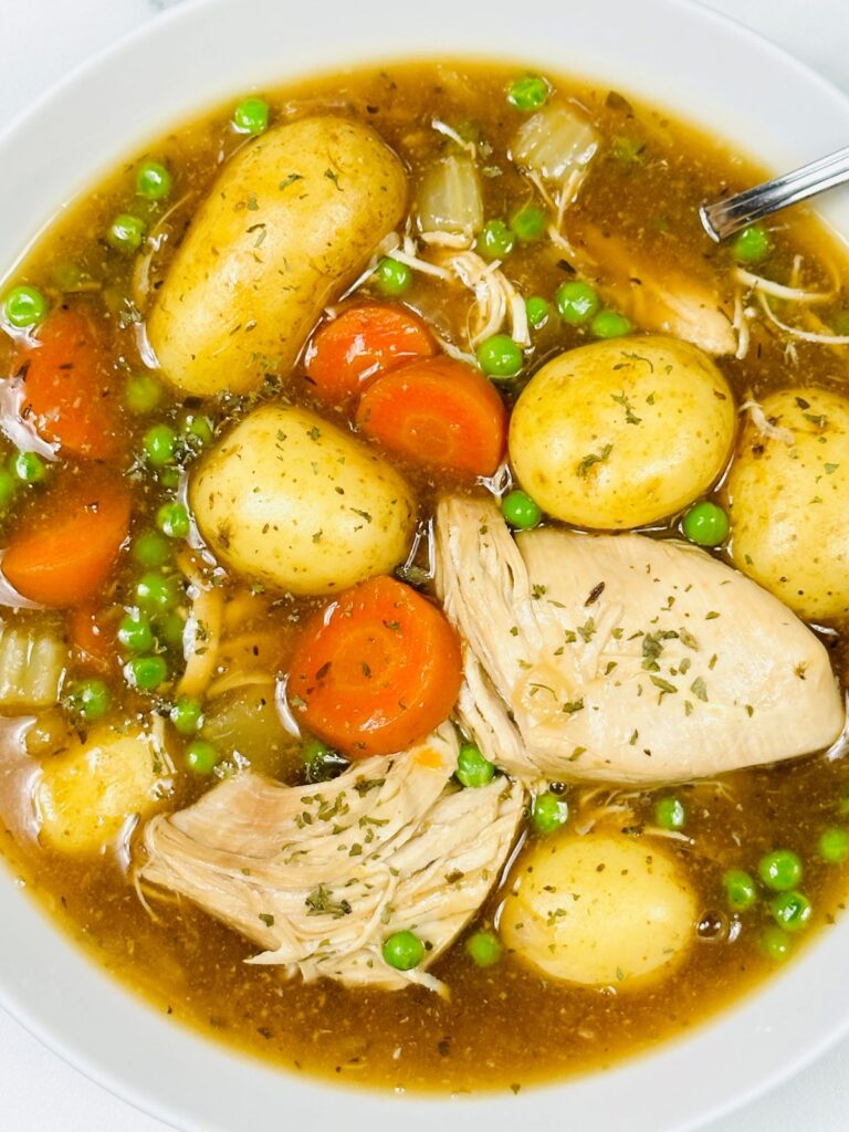 chicken casserole in a bowl including chicken, carrots, peas, celery and gravy