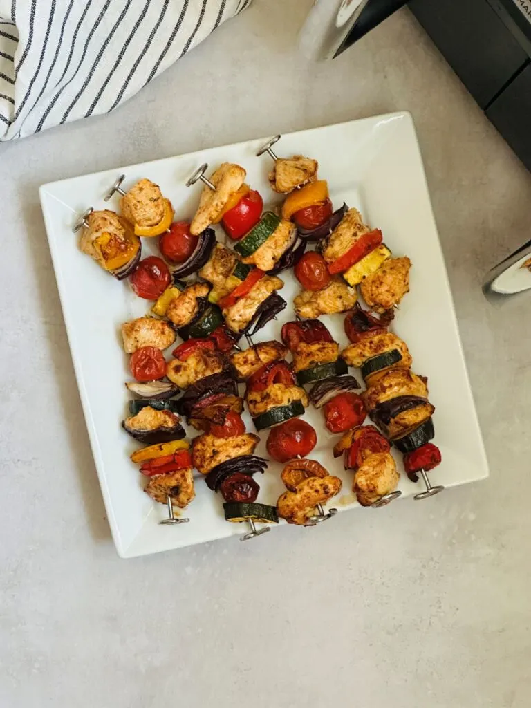 chicken kebabs on plate next to air fryer