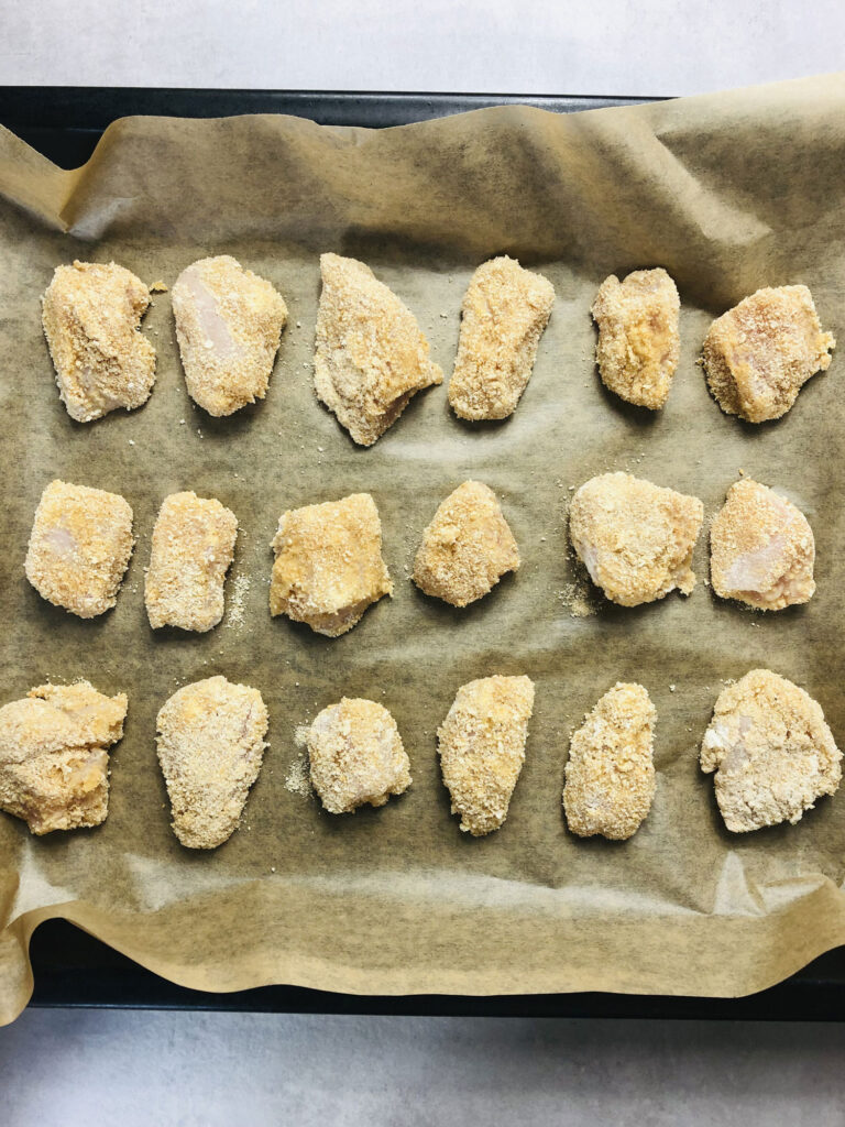 chicken nuggets spread out on baking tray