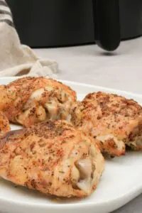 four chicken thighs on a plate next to an air fryer
