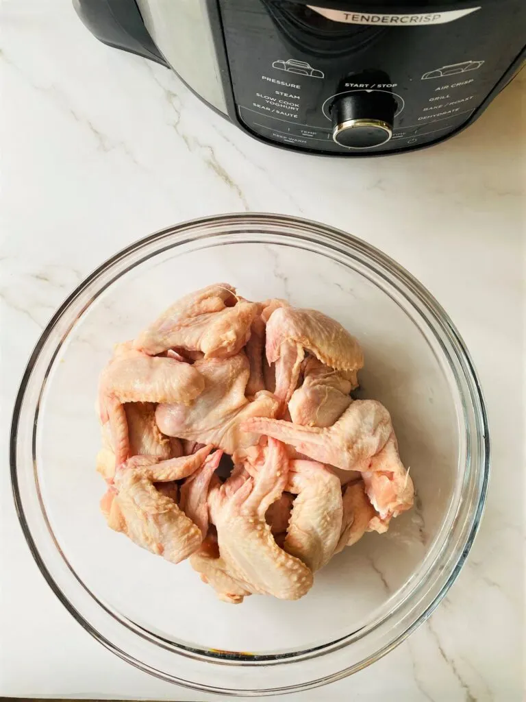 raw chicken wings in bowl next to Ninja Foodi Air Fryer 