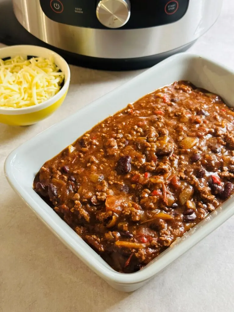 chilli con carne with cheese next to Ninja Foodi