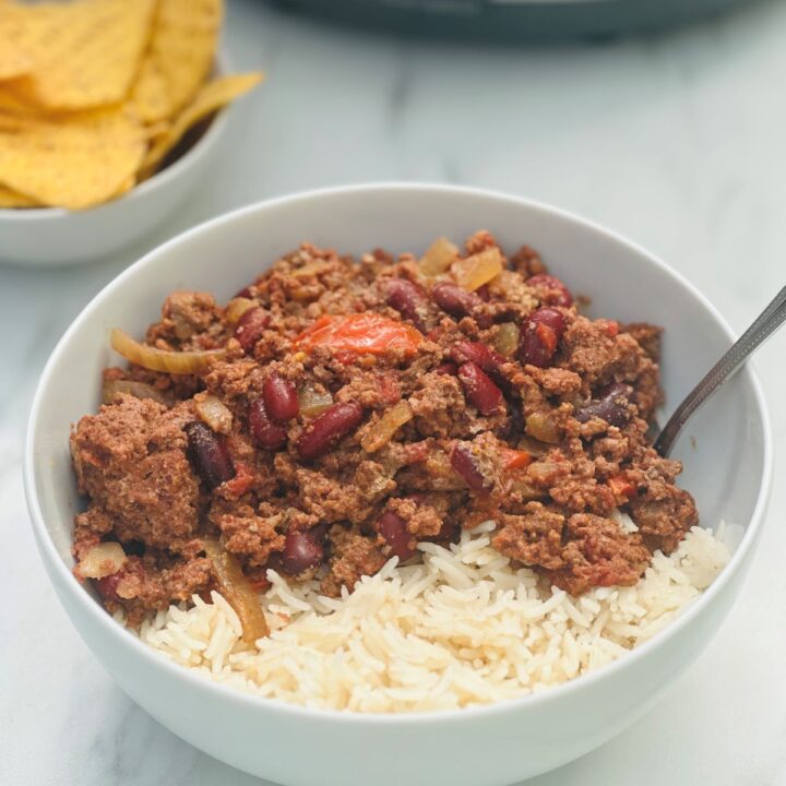 bowl of chilli con carne and rice next to some tortilla chips with slow cooker
