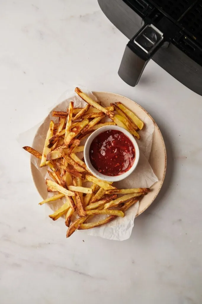 chips on plate with sauce next to air fryer