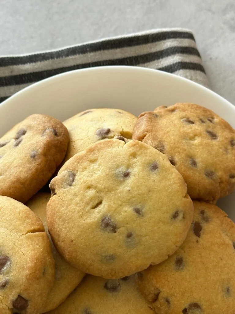 hocolate chip shortbread cookies piled in a white bowl on a striped cloth