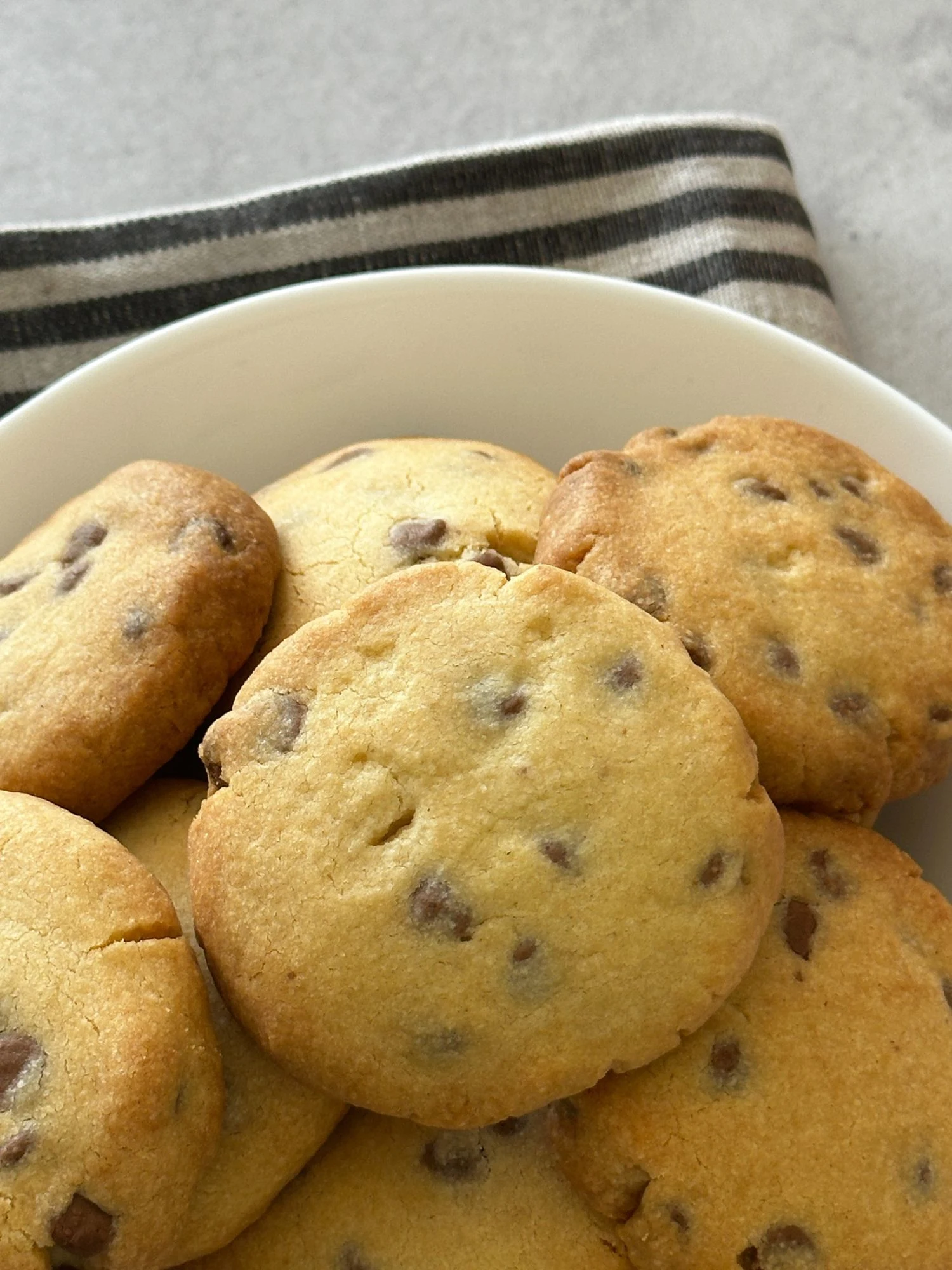 hocolate chip shortbread cookies piled in a white bowl on a striped cloth