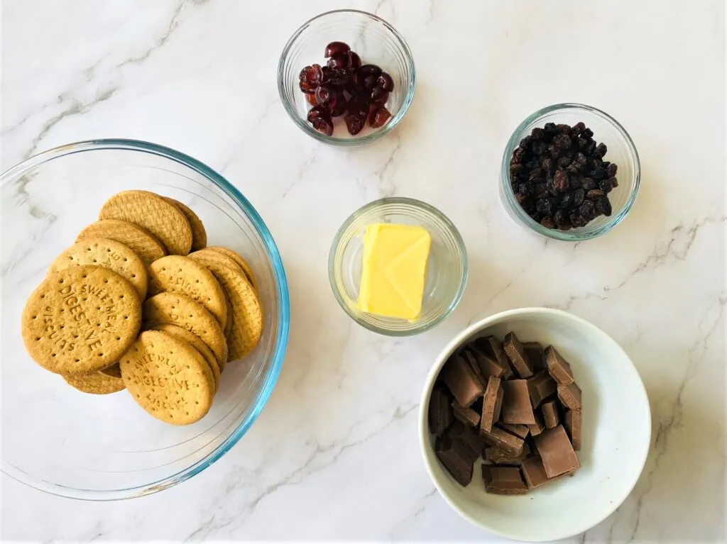 chocolate fridge cake ingredients - digestive biscuits, butter, raisins, glace cherries, chocolate