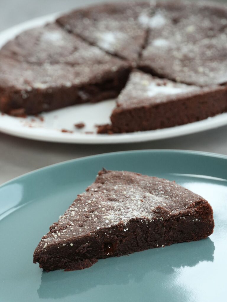 slice of chocolate shortbread on a blue plate in front of a plate with the rest of the shortbread on  