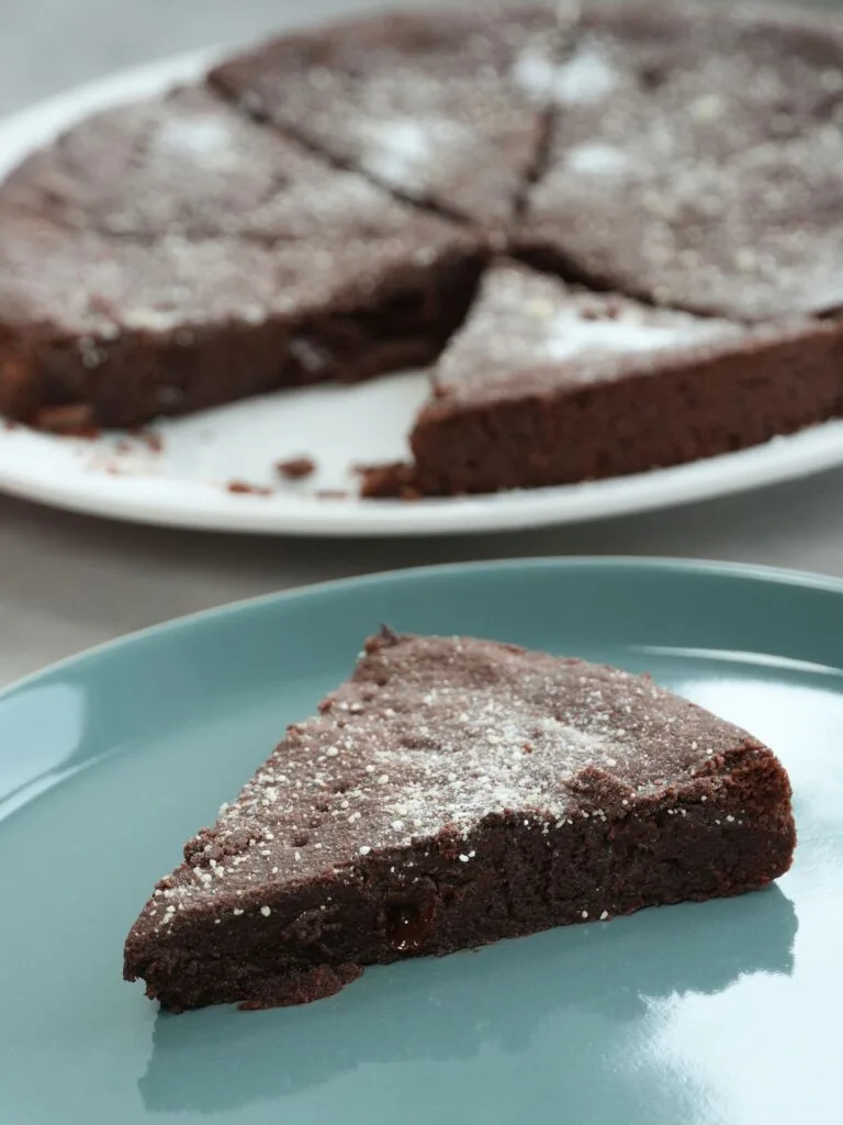 slice of chocolate shortbread on a blue plate in front of a plate with the rest of the shortbread on