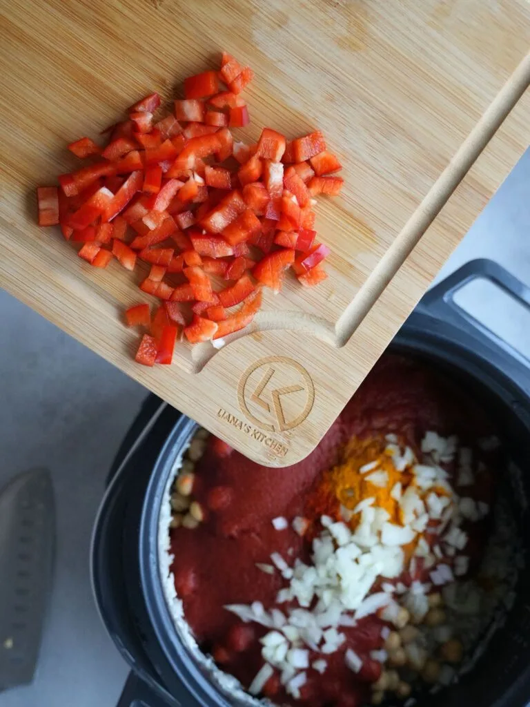 adding chopped red pepper to a rice cooker