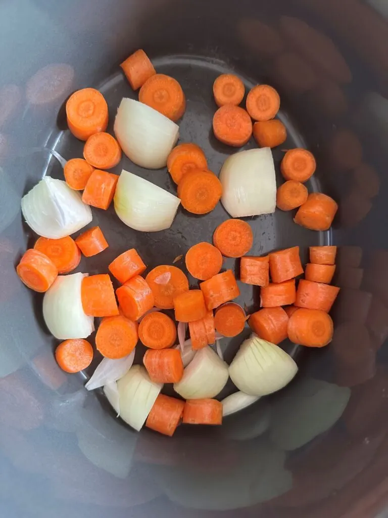 raw chopped carrot and onions in slow cooker