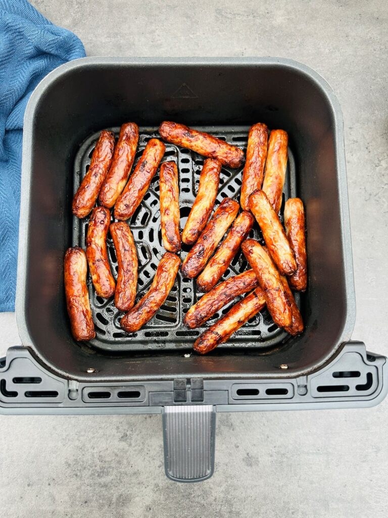 cooked chipolatas in an air fryer basket