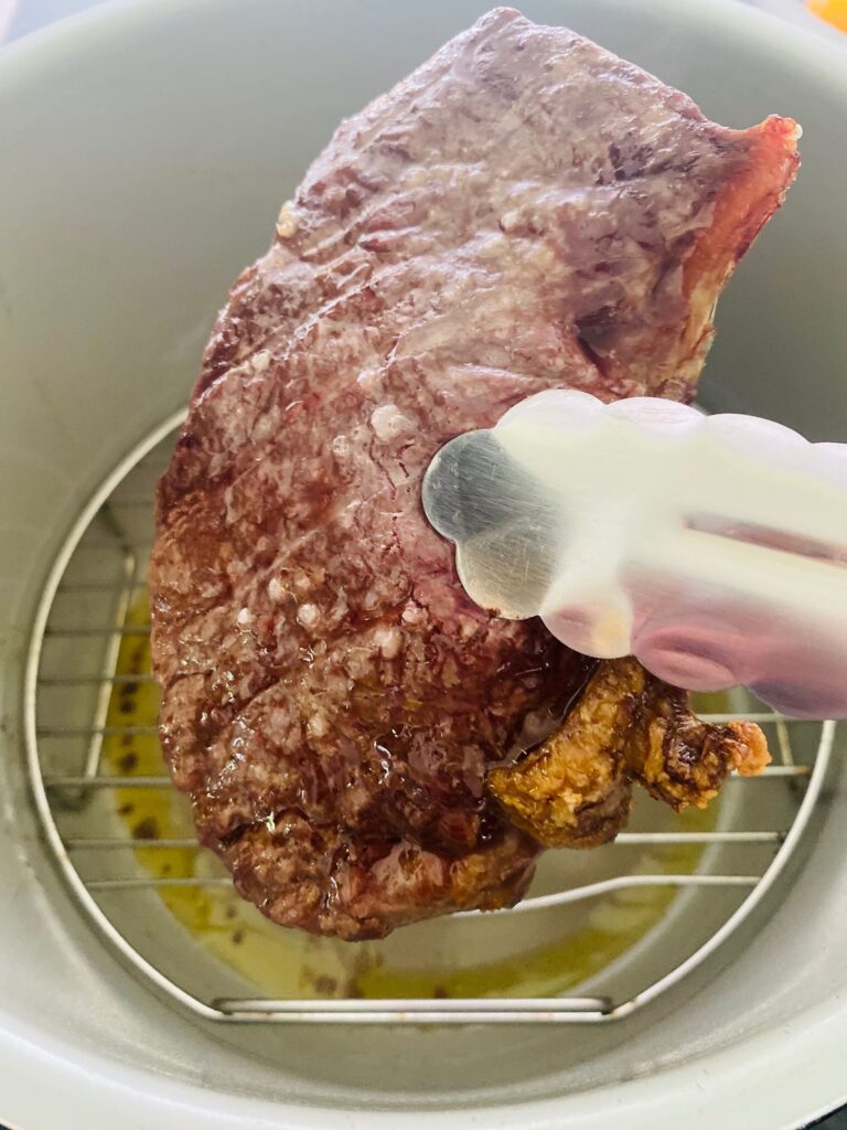 air fryer steak in tongs