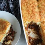 cottage pie in a white oven dish with a portion taken out and put in a serving bowl next to it