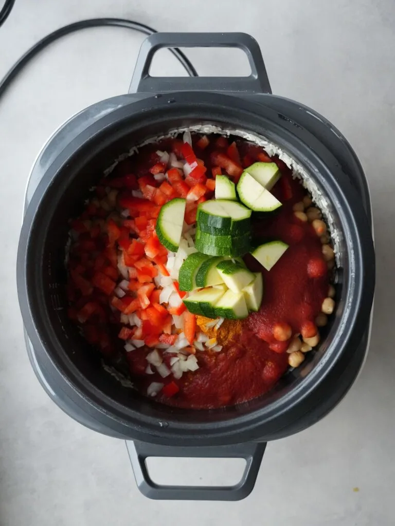 rice cooker filled with rice, passata, red peppers, onion, courgette, chickpea, split red lentils and spices
