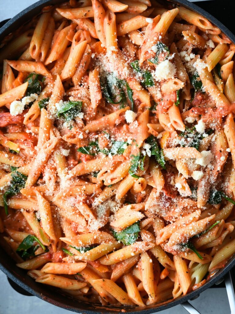 creamy tomato pasta with spinach and grated parmesan cheese sprinkled on top