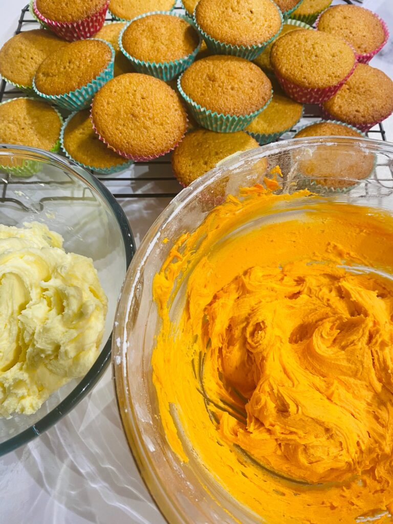 cupcakes and orange buttercream icing ready for decorating for Halloween