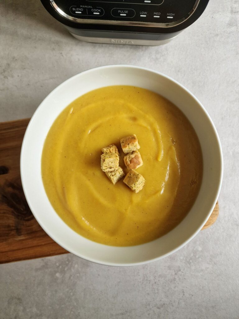curried parsnip soup in a bowl next to a Ninja soup maker