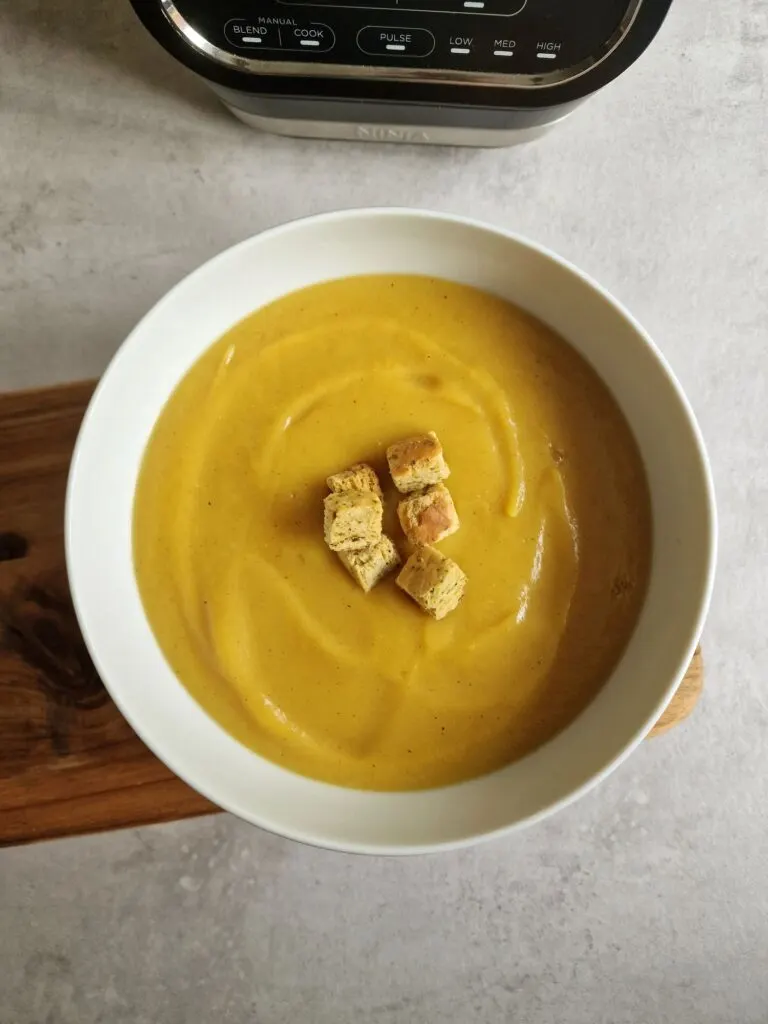 curried parsnip soup in a bowl next to a Ninja Soup maker