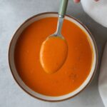 curried lentil soup in a bowl with a spoon above it next to a Ninja soup maker