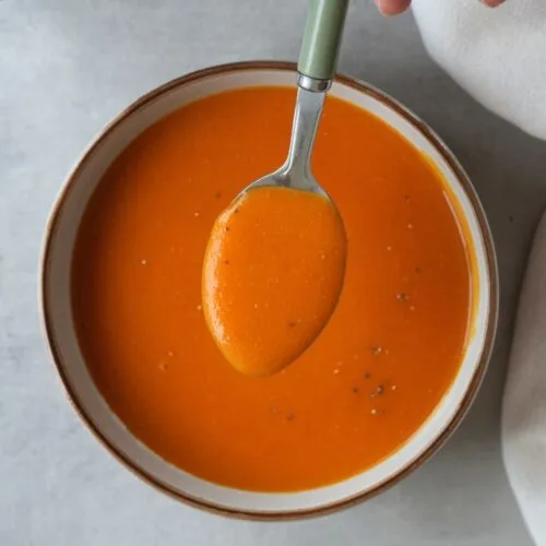 curried lentil soup in a bowl with a spoon above it next to a Ninja soup maker
