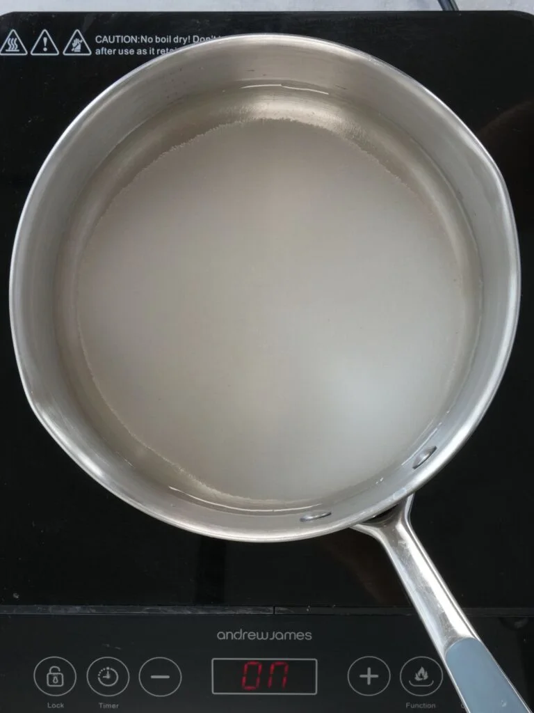 saucepan of water with sugar dissolving in it on top of a hob