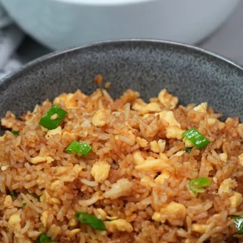 egg fried rice in two seperate bowls with spring onion on top