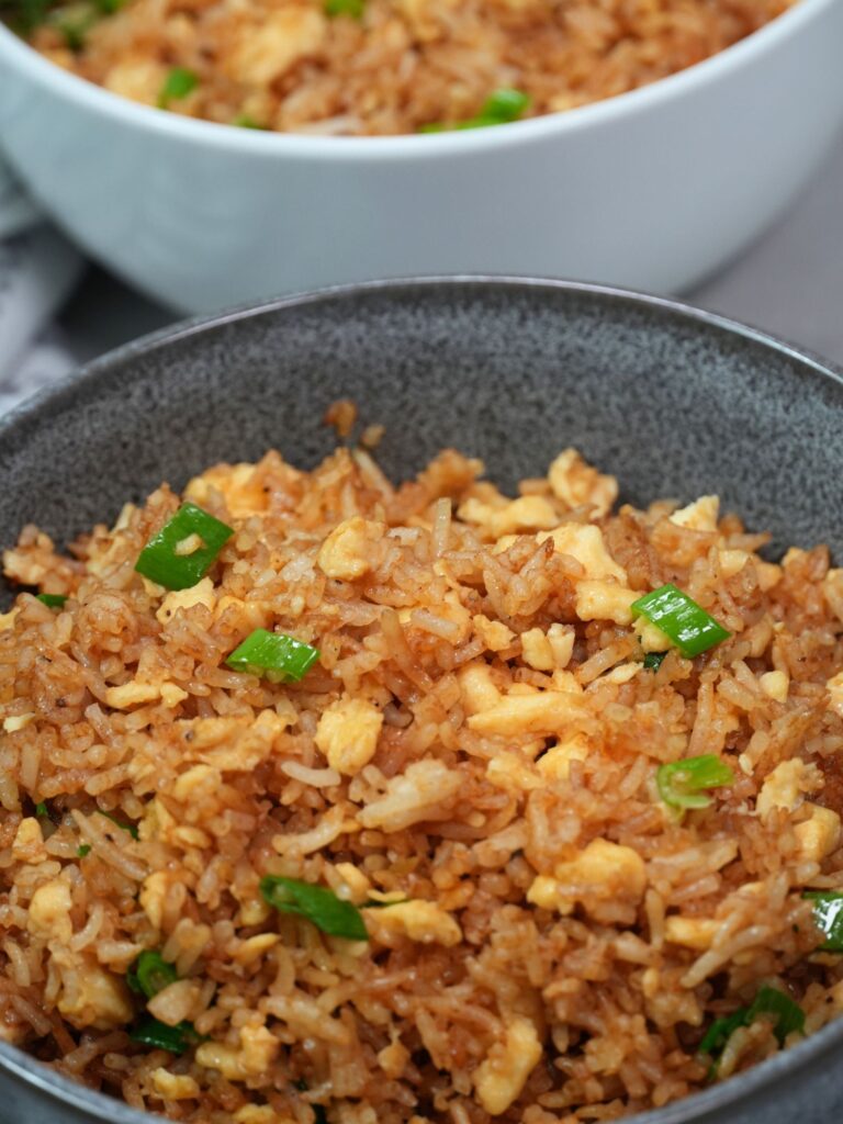 egg fried rice in two seperate bowls with spring onion on top