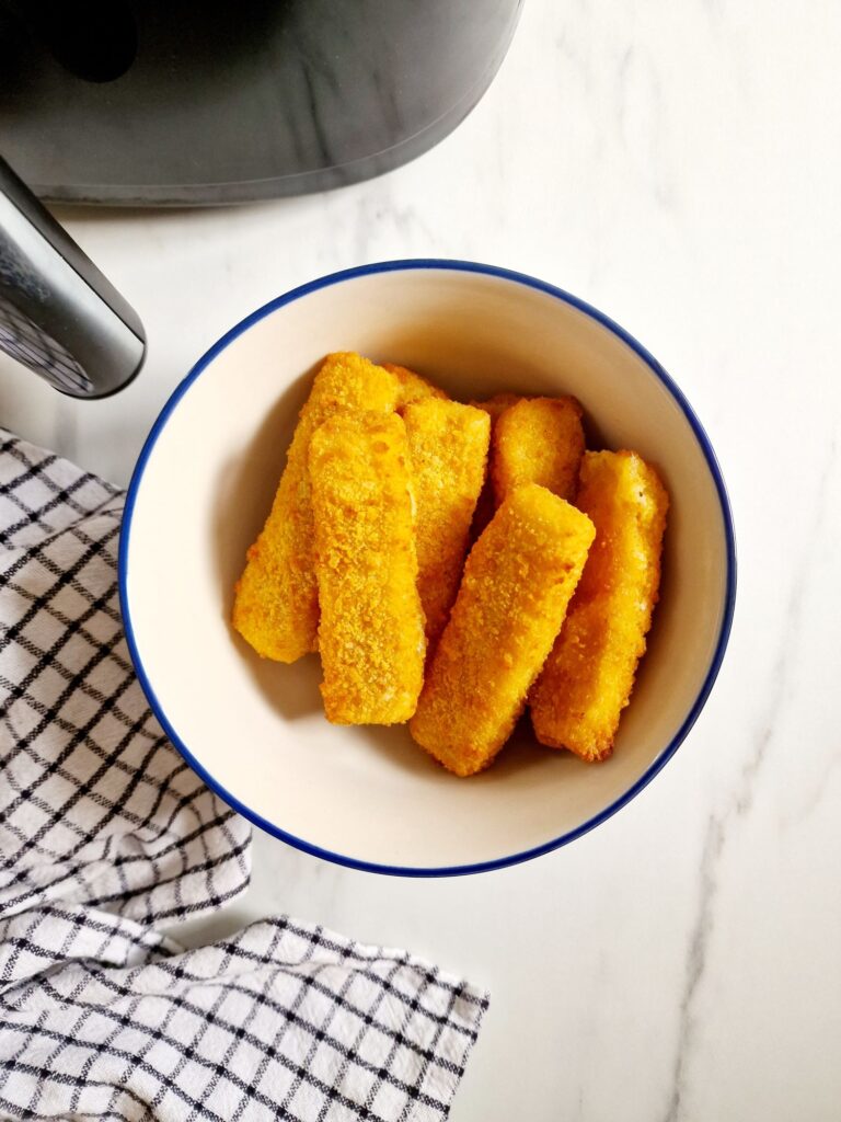 fish fingers in bowl next to the air fryer