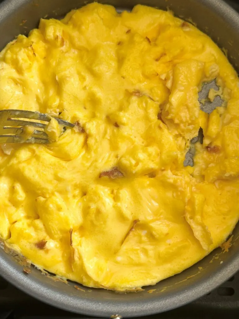 fluffing scrambled egg in baking tin during air fryer cooking time