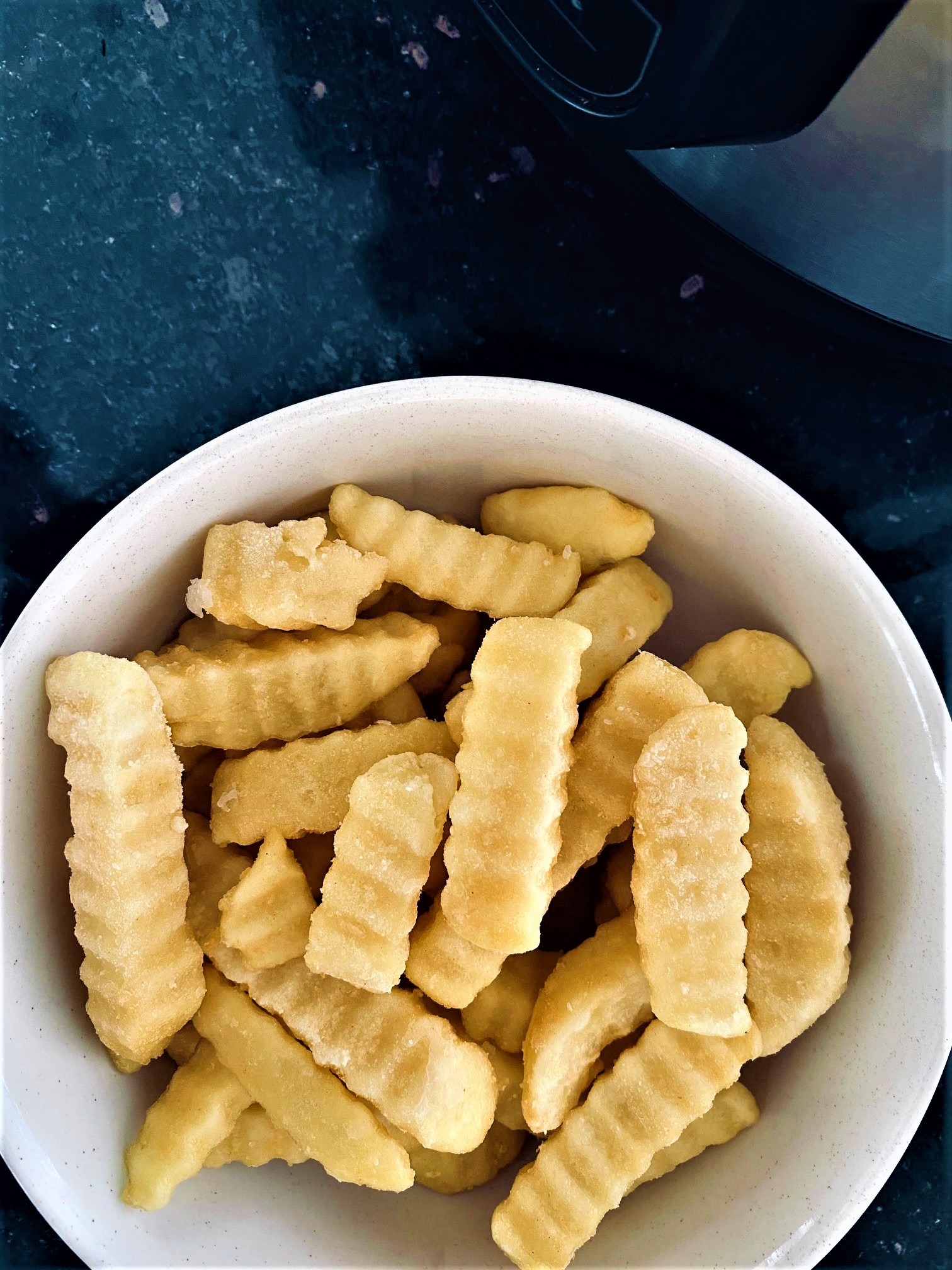 frozen chips in bowl next to air fryer
