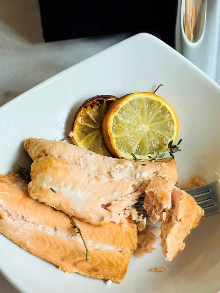 cooked salmon with lemons next to air fryer