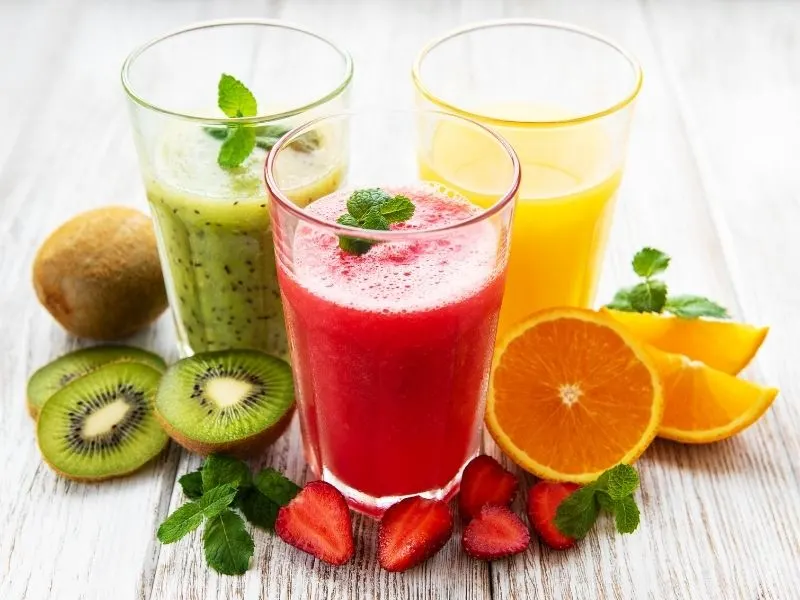 3 glasses with smoothies and fresh fruit next to them