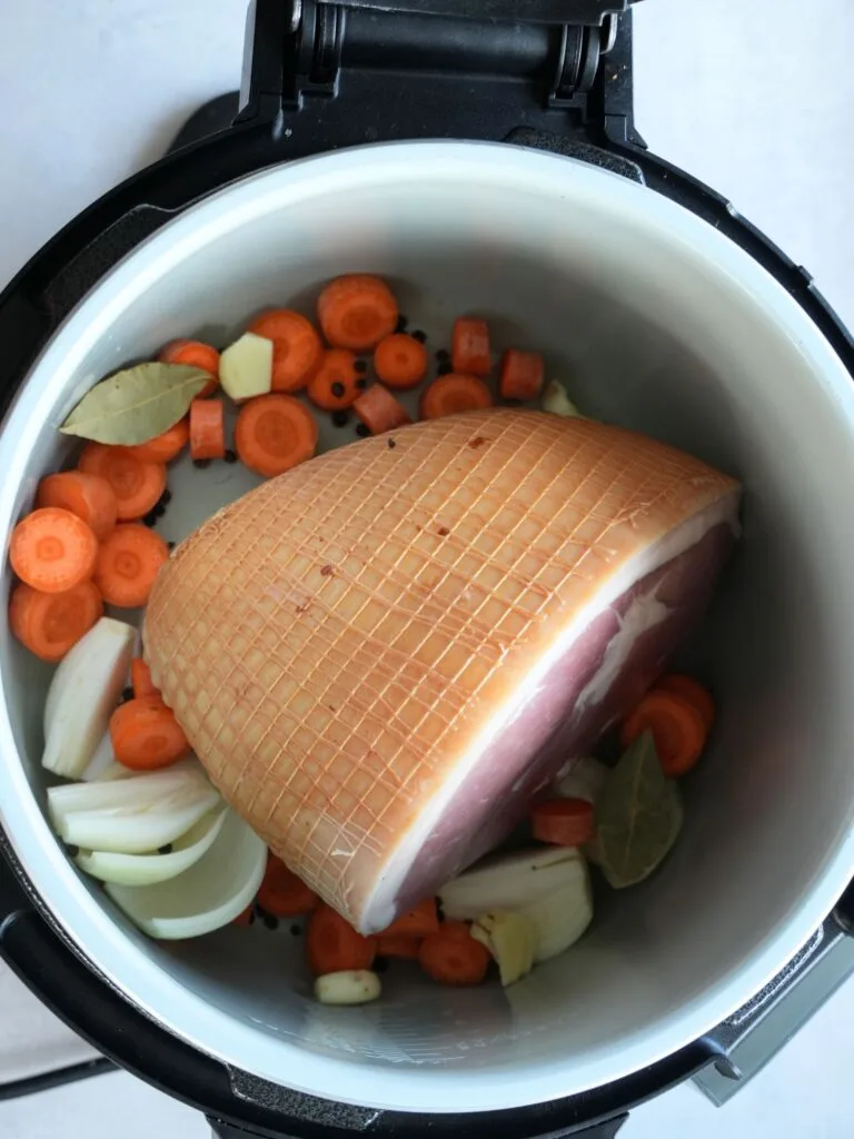 raw gammon joint in a Ninja Foodi 15 in 1 with vegetables surrounding it