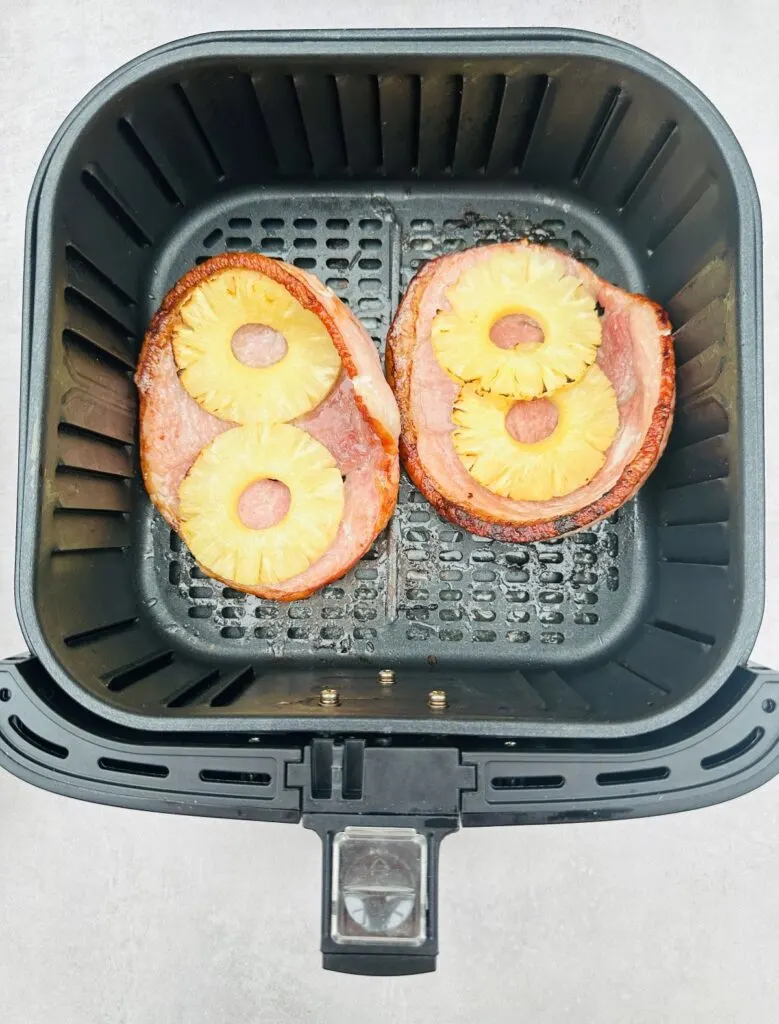 two cooked air fryer gammon steaks with two grilled pineapple rings on each one