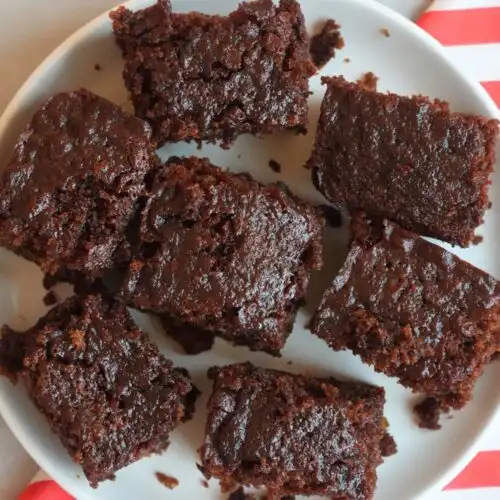ginger cake sliced into squares on a white plate sitting on top of a red and white cloth