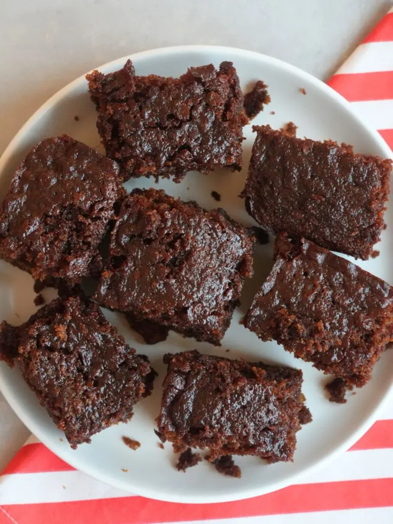 ginger cake sliced into squares on a white plate sitting on top of a red and white cloth