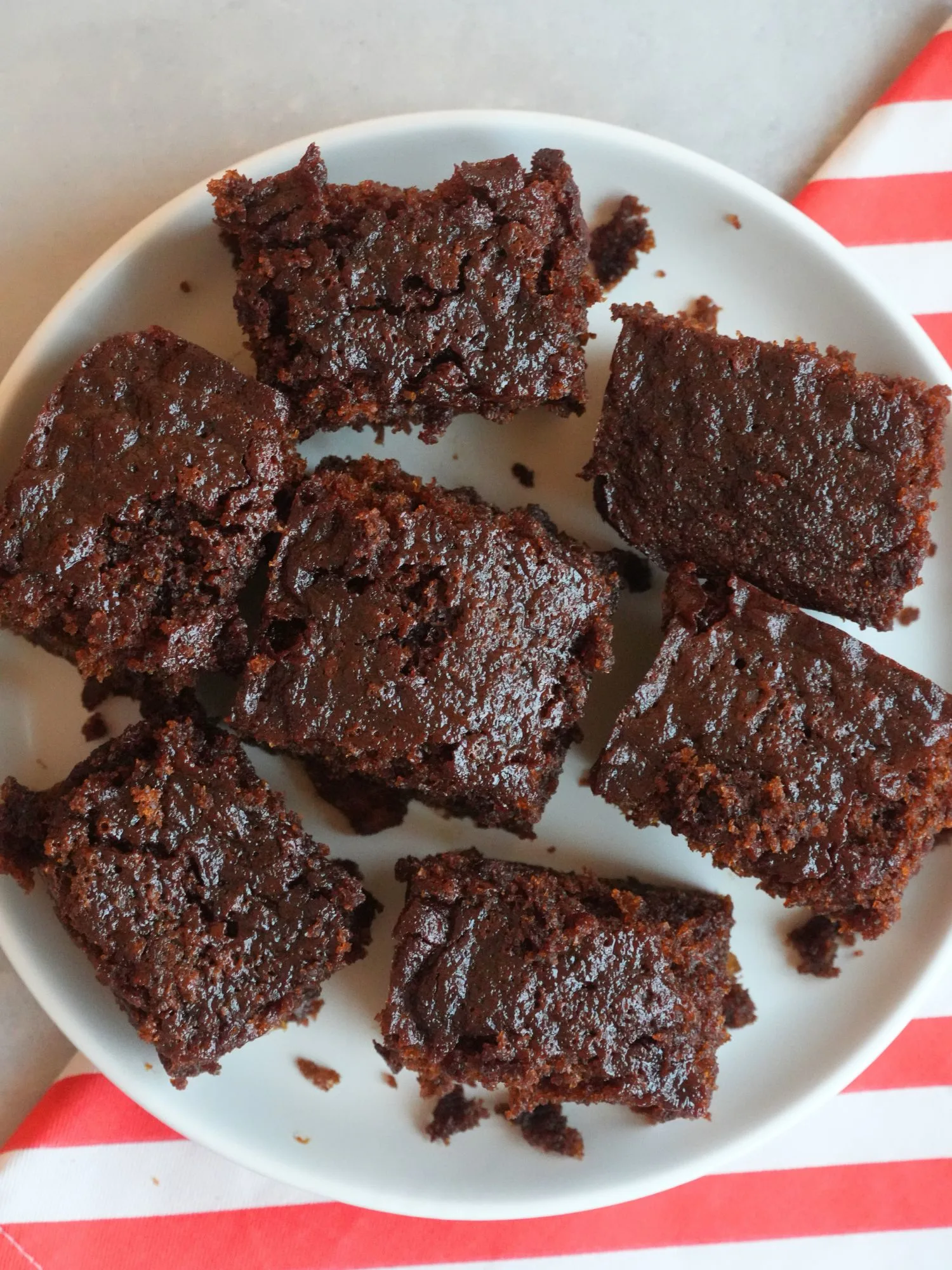 ginger cake sliced into squares on a white plate sitting on top of a red and white cloth