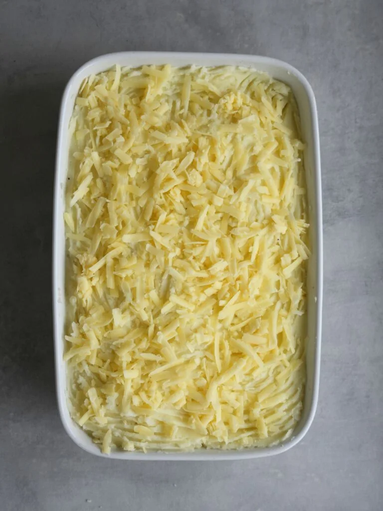 grated cheese on top of cottage pie ready to be cooked